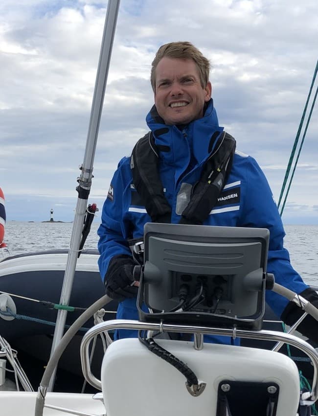 Marius smiler ved rattet på en seilbåt.